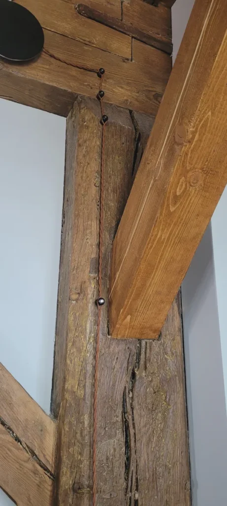 Rudas tekstilinis laidas ant izoliatorių medinėje konstrukcijoje
