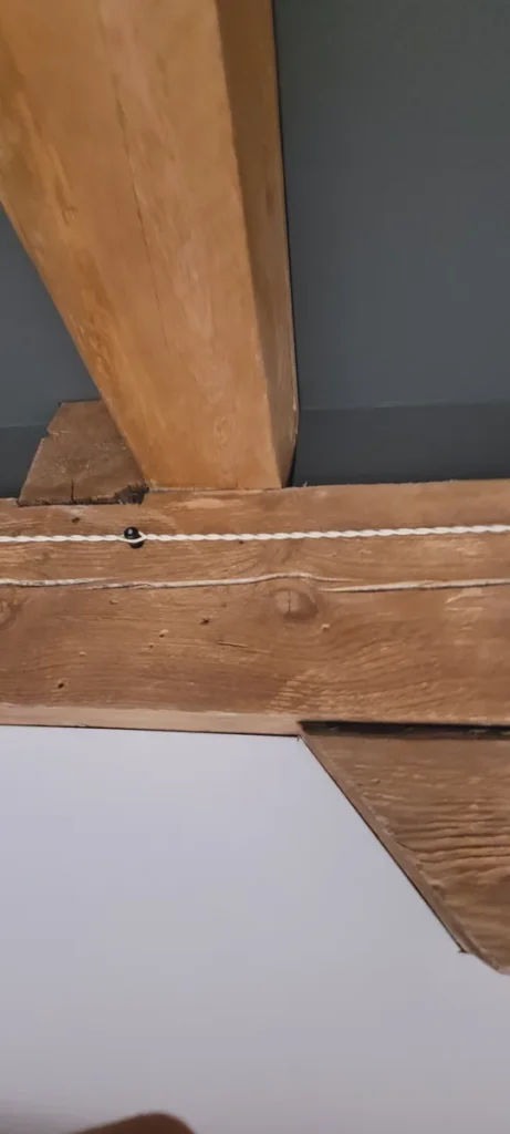 Baltas pintas tekstilinis laidas ant juodų izoliatorių